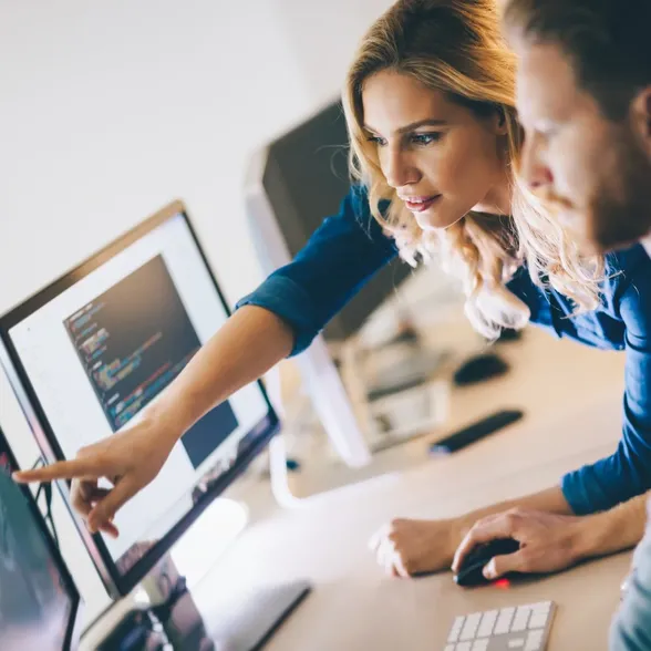 Zwei Mitarbeitende arbeiten gemeinsam an einem Computerarbeitsplatz